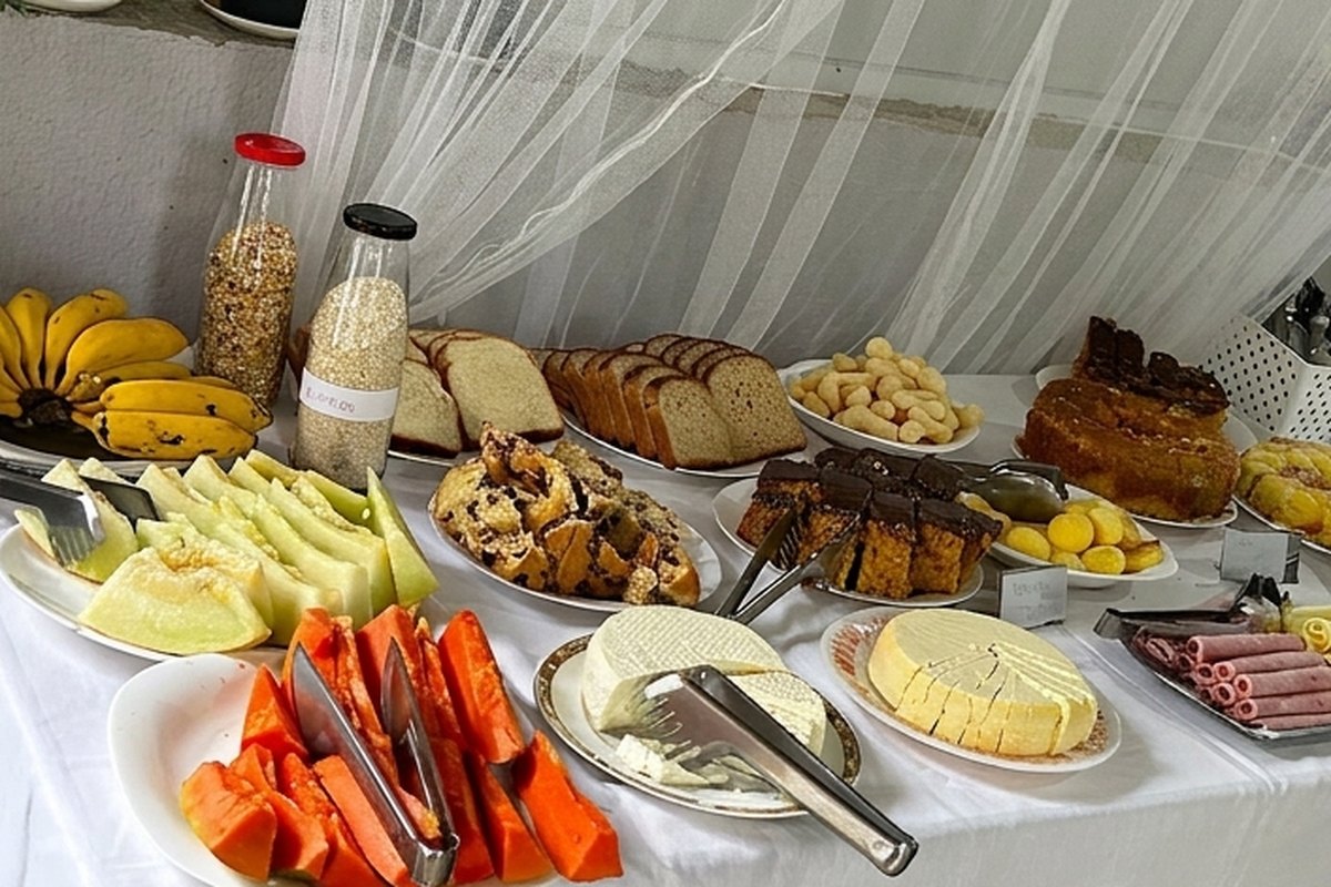 Mesa de café da manhã com frutas, pães, bolos e frios