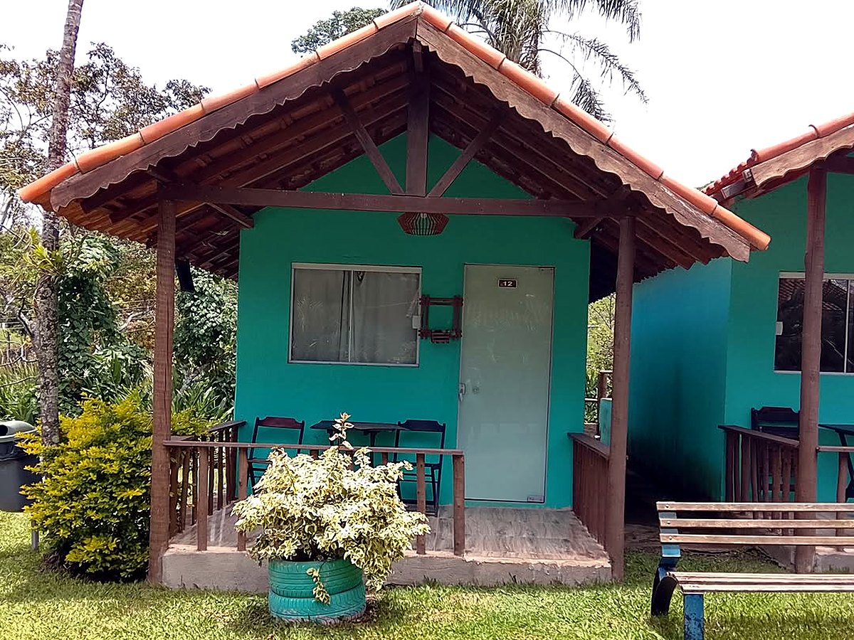 Chalé com varanda de madeira, de frente pro gramado